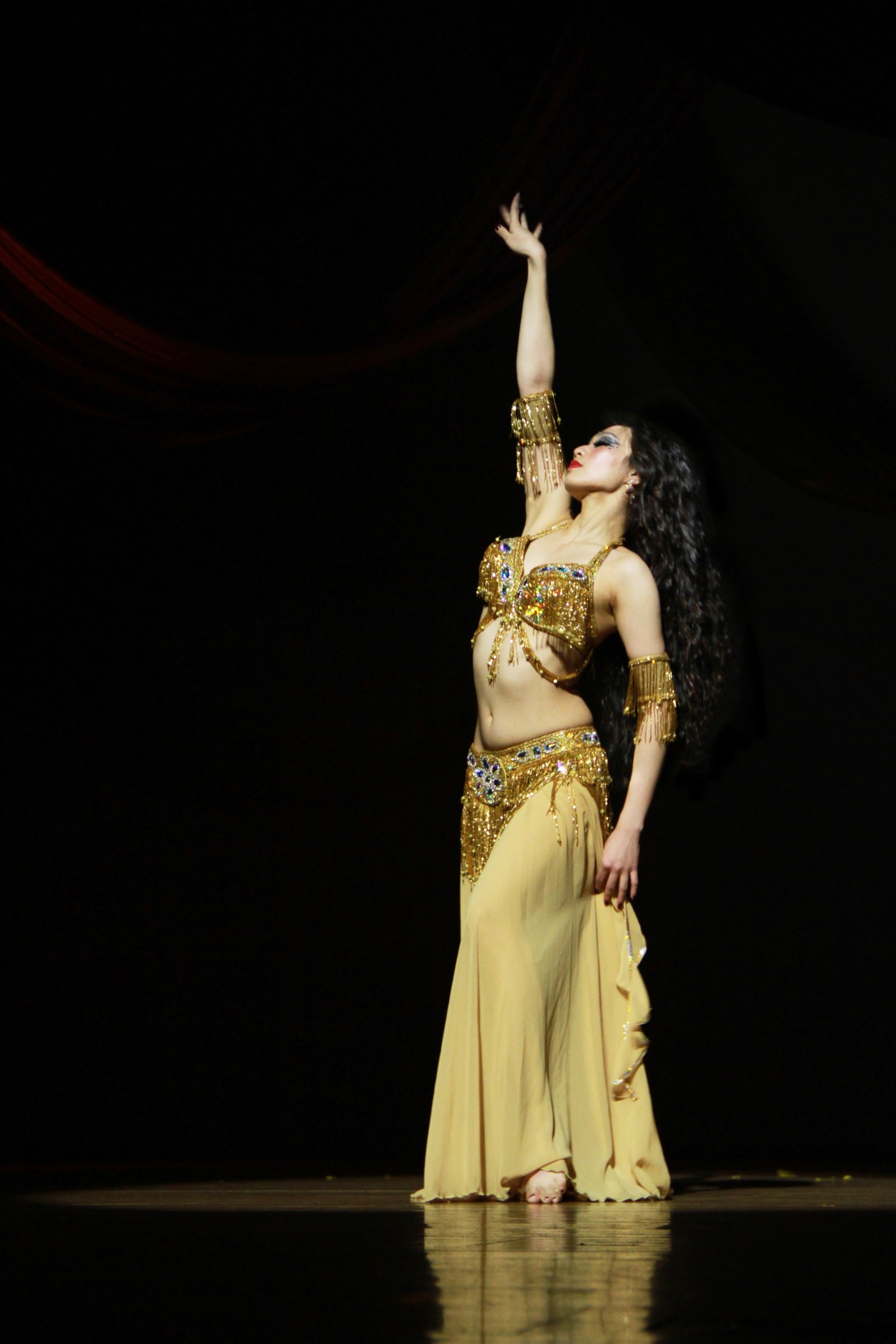 Iveta Chen performing in a gold costume on a dark stage